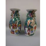 A PAIR OF ORIENTAL BALUSTER VASES, decorated with figures in landscapes, moulded dog of fo twin