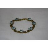 A TOPAZ BRACELET, with seven oval facted topaz stones with butterfly link detail, stamped 10k,