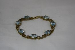 A TOPAZ BRACELET, with seven oval facted topaz stones with butterfly link detail, stamped 10k,