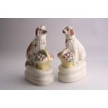 A NEAR PAIR OF 19TH CENTURY STAFFORDSHIRE SEATED SPANIELS, with gilt collars and basket of