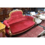 A VICTORIAN WALNUT FRAMED SOFA, with raised back and red buttoned upholstery, together with an
