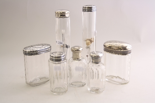 A SET OF FOUR SILVER TOPPED GLASS DRESSING TABLES BOTTLES, all monogrammed, tallest 18cm, an oval