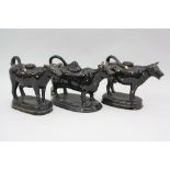 THREE 19TH CENTURY BLACK GLAZED 'JACKFIELD' COW CREAMERS, with gilt highlights, all with loop tails,