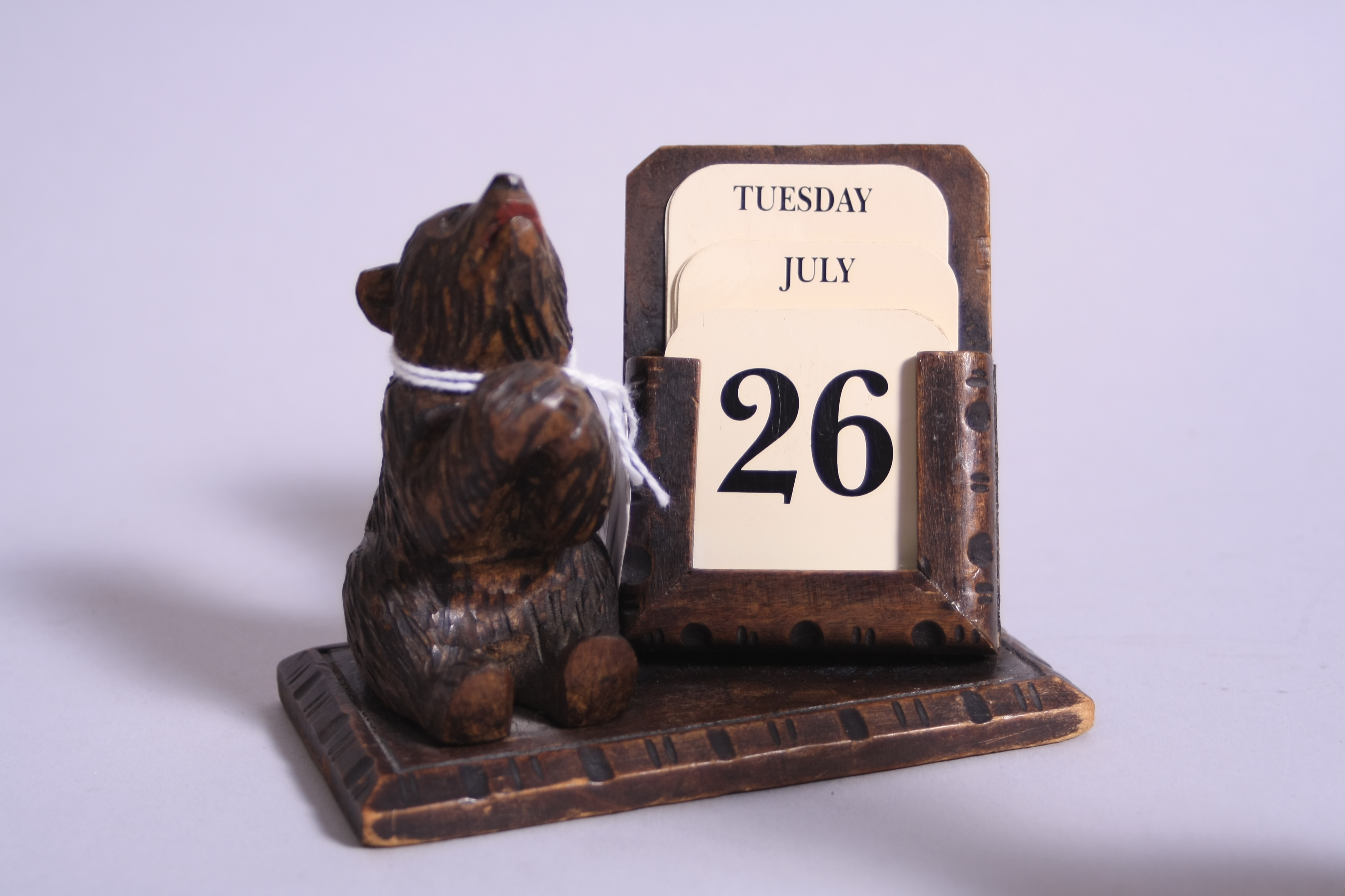 A CARVED BLACK FOREST STYLE DESK CALENDAR, mounted with bear