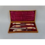 A CASED CARVING SET, having silver mounts to pistol grips and collars, with embossed scroll, shell