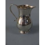 A SILVER MILK JUG, of plain baluster form, high loop handle, ribbed foot, London 1987, approximately