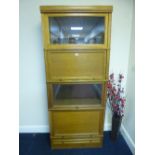 A LIGHT OAK PART GLAZED FOUR SECTION BOOKCASE/CABINET, with drawer below, approximate size width