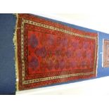 A RED GROUND RUG, with blue and black lozenge style pattern with border, approximate size 220 cm x