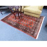 A RED GROUND RUG, with medallion style pattern with border, approximate size 188cm x 125cm