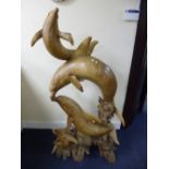 A LARGE CARVED HARDWOOD FIGURE OF FOUR DOLPHINS, with naturalistic base (sd)