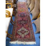 A NORTH WEST PERSIAN RUNNER, circa 1900, the madder red field bearing alternate colour medallion