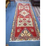 AN IRANIAN RED GROUND WOOL, CARPET RUNNER, approximate size 296cm x 114cm