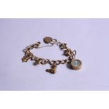 A 9CT CHARM BRACELET, with seven mixed charms and locket, approximate weight 28.9 grams