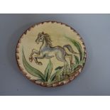 A PUIGDEMONT SLIPWARE CIRCULAR WALL PLAQUE, decorated with grey horse rearing, signed verso,