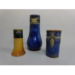 THREE ROYAL DOULTON VASES, cylindrical example with relief flower and grape swag, impressed R M