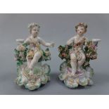 TWO 18TH CENTURY DERBY SEATED CHERUB CHAMBERSTICKS, c.1770, both wearing floral robes with floral