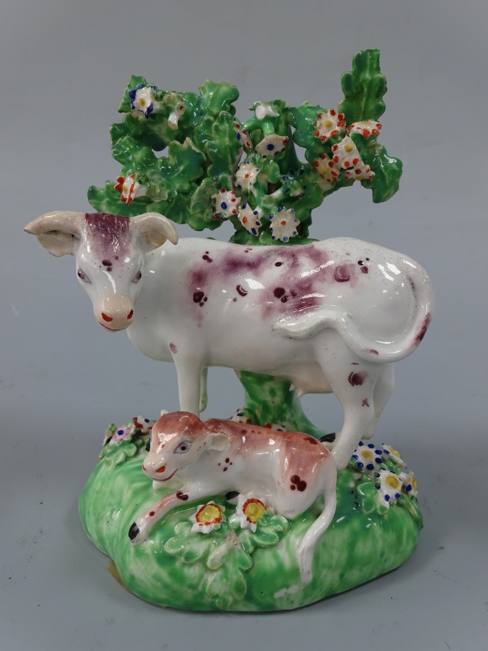 A DERBY FIGURE GROUP, c.1800, modelled as recumbent calf before standing cow with floral bocage