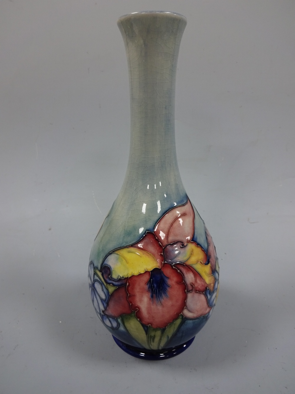 A MOORCROFT FOOTED BOTTLE VASE, with flared neck, tube line decorated with frilled orchid pattern to