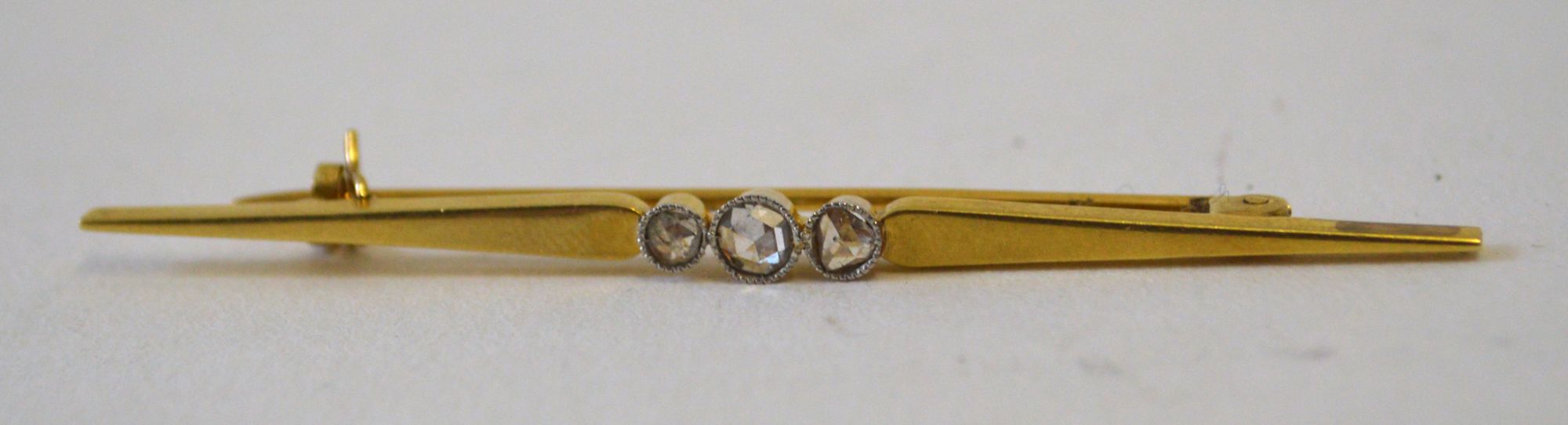 A late 19th century unmarked gold bar brooch, set with three rose cut diamonds, approx 6.5cm.