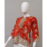 A Chinese child's robe, early 20th century, couched silver thread on a red silk ground.