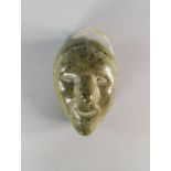 An Inuit soap stone carving of an oval face, 20th century, the head with stylised hair, the face