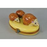 A Limoges enamel decorative box, 20th century, with a group of three hedgehogs, on a yellow base,