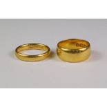 A wide 22ct gold wedding band, approx size J, together with another 22ct gold wedding band,