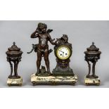 A  three piece clock garniture 
Surmounted with cupid, on variegated white marble base.  46 cm high.