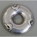 A Liberty & Co. silver brooch
Of circular form, in the manner of Archibald Knox.  5.25 cm diameter.