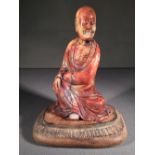 A Chinese carved hardstone figure of a sage
Worked kneeling on a carved wooden  base.  14.5 cm high.