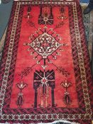 A Caucasian wool rug
The wine red field enclosing a central medallion with stylised pendant