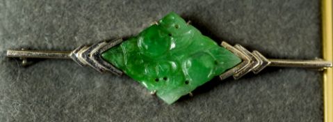 An Art Deco white gold and green jade bar brooch
Of carved lozenge form.  5.25 cm wide.