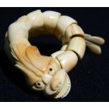 A Chinese carved coral bracelet
Formed as a reticulated dragon.  30 cm long.