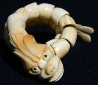 A Chinese carved coral bracelet
Formed as a reticulated dragon.  30 cm long.