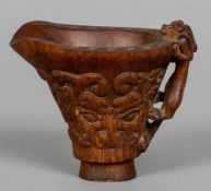 A carved horn libation cup
The handle a mythical beast, the body with archaistic band.  9 cm high.