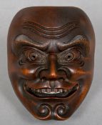 A late 19th century Japanese carved wooden netsuke
Modelled as a figural mask.  5.75 cm high.