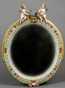 A Meissen porcelain mirror
Of oval form, surmounted with two cherubs holding a floral garland,