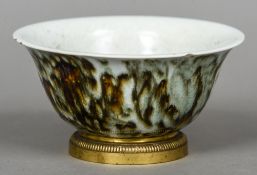 A Chinese celadon bowl
The exterior with mottled decoration, standing on an ormolu mount.