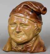 A 19th century salt glaze character mask flask
Of large proportions, modelled wearing a bow tie.