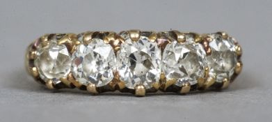 An 18 ct gold diamond five stone ring
The claw set stones above incised shoulders.