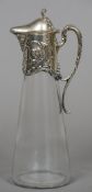 A small Sterling silver mounted clear glass claret jug With scrolling handle and floral decorations.