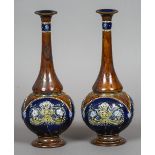 A pair of Doulton Lambeth pottery vases Each with tall slender neck, the bodies typically decorated,
