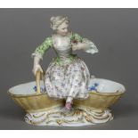 A late 19th/early 20th century Meissen porcelain figural salt Modelled as a girl seated on two