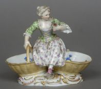 A late 19th/early 20th century Meissen porcelain figural salt Modelled as a girl seated on two