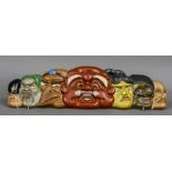 A Japanese painted carved wooden wall plaque Formed as various theatrical masks. 90 cm wide.