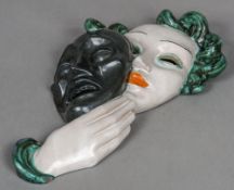 An Art Deco Goldscheider wall mask Formed as a young woman holding a mask,