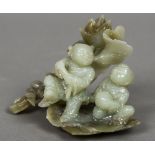 A Chinese carved jade figural group Formed as two children before foliage. 13 cm wide.