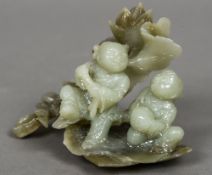 A Chinese carved jade figural group Formed as two children before foliage. 13 cm wide.