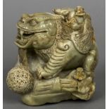 A Chinese carved soapstone group Worked as figures attending an oversized mythical beast.
