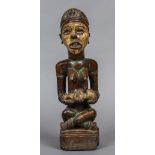 A tribal carved hardwood polychrome decorated figure Modelled seated holding a infant. 39.